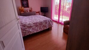 A bedroom with a bed, a television, and a window with curtains.