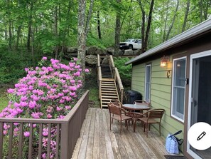 Enjoy outdoor dining or relaxation on the deck, surrounded by lush greenery and a scenic view.