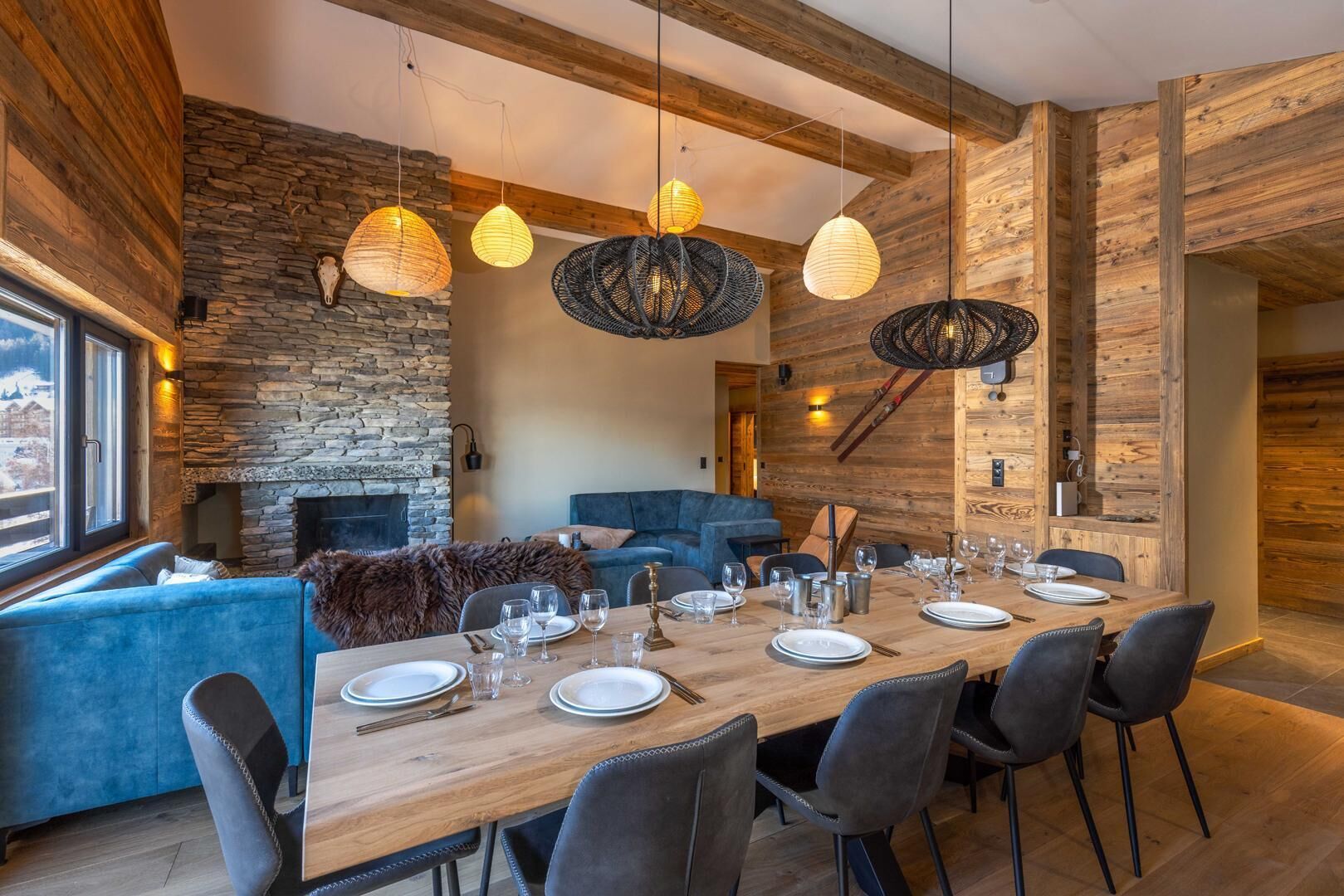 A dining area with a wooden table set for six, a stone fireplace, and a blue sofa.
