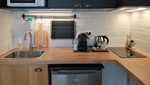A compact kitchen with a microwave, coffee maker, kettle, and a sink. - Studios confort  VILLA VOLTAIRE (Clamart)