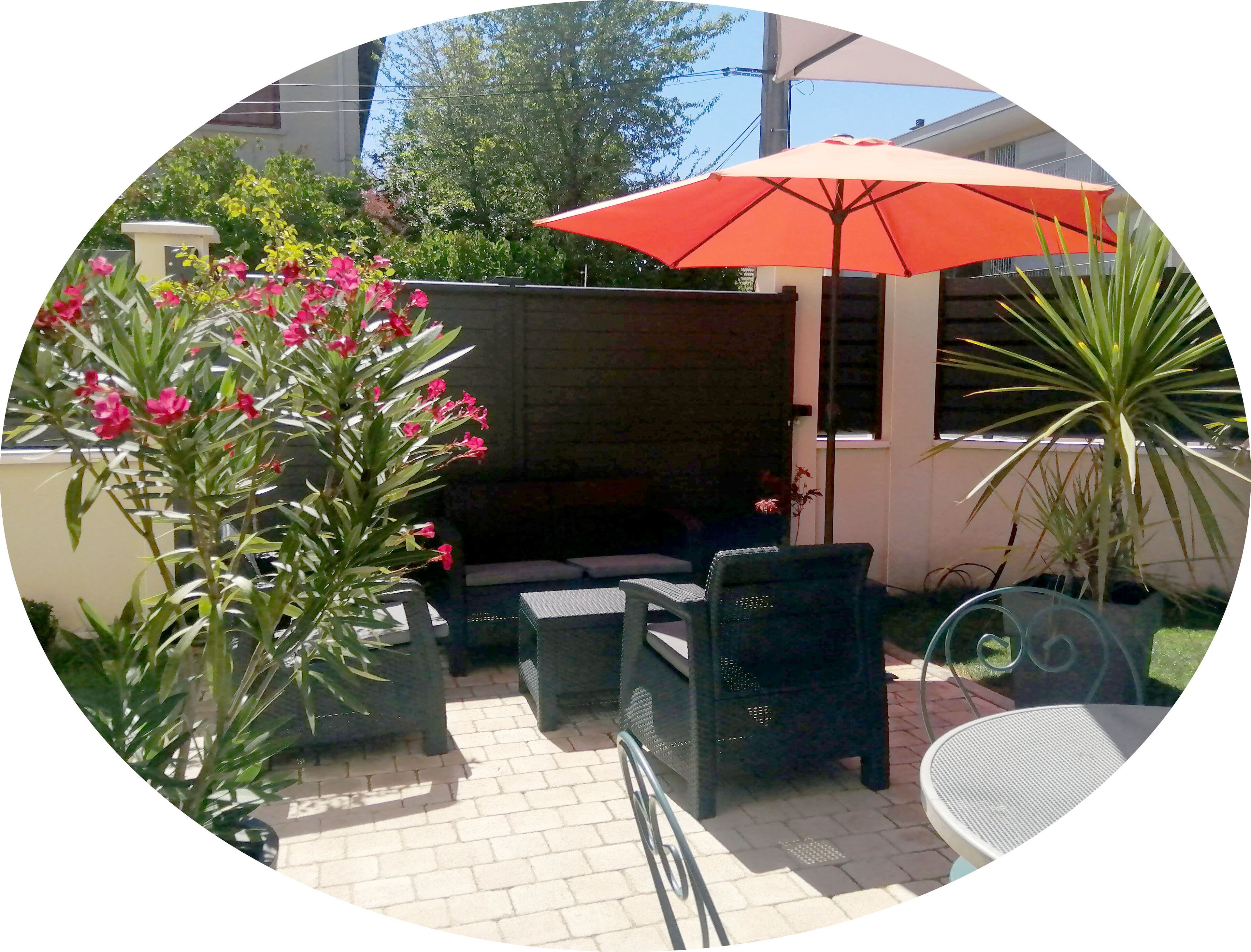 An outdoor patio area with seating, an umbrella, and potted plants.