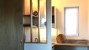 A kitchen with a window, a sink, and two stools. - Studios confort  VILLA VOLTAIRE (Clamart)