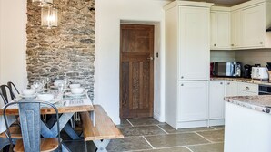 Un coin repas avec un mur en pierre, une porte en bois et des meubles blancs.