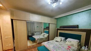 Ein Schlafzimmer mit einem Bett, einer Bank, einem Kleiderschrank und einem Spiegel.