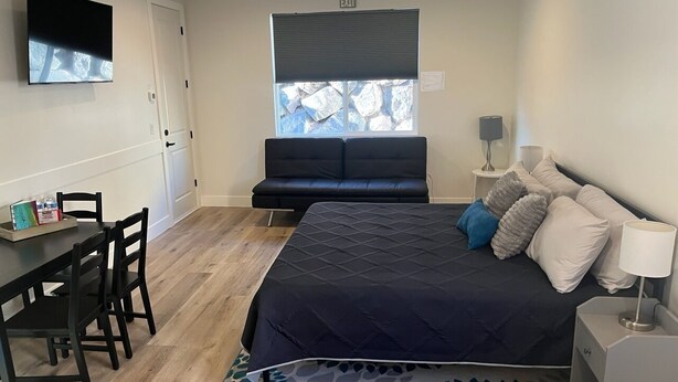 A bedroom with a bed, a desk, a chair, a TV, a window with blinds, and a ceiling fan. - Cozy Casita by Sand Hollow and Zion (Hurricane)