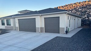 A single-story house with a garage, a driveway, and a stone wall in the background. - Cozy Casita by Sand Hollow and Zion (Hurricane)