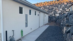A building with a stone wall and a concrete pathway leading to a door. - Cozy Casita by Sand Hollow and Zion (Hurricane)
