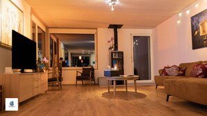 A modern living room with a flat-screen TV, wooden furniture, a round table, and a sofa with patterned cushions. - Casa Teatro Panoramico (Locarno)