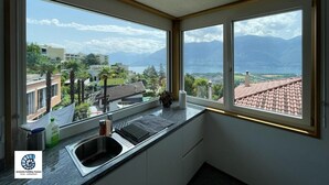A kitchen with large windows offering a view of mountains and a lake. - Casa Teatro Panoramico (Locarno)