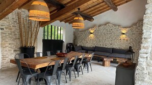 Un comedor rústico con una larga mesa de madera, sillas negras e lámparas de fibra.