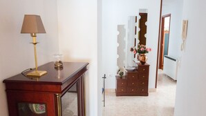 Un passadís amb una taula consola de fusta, una làmpada i un moble d'armari amb mirall.