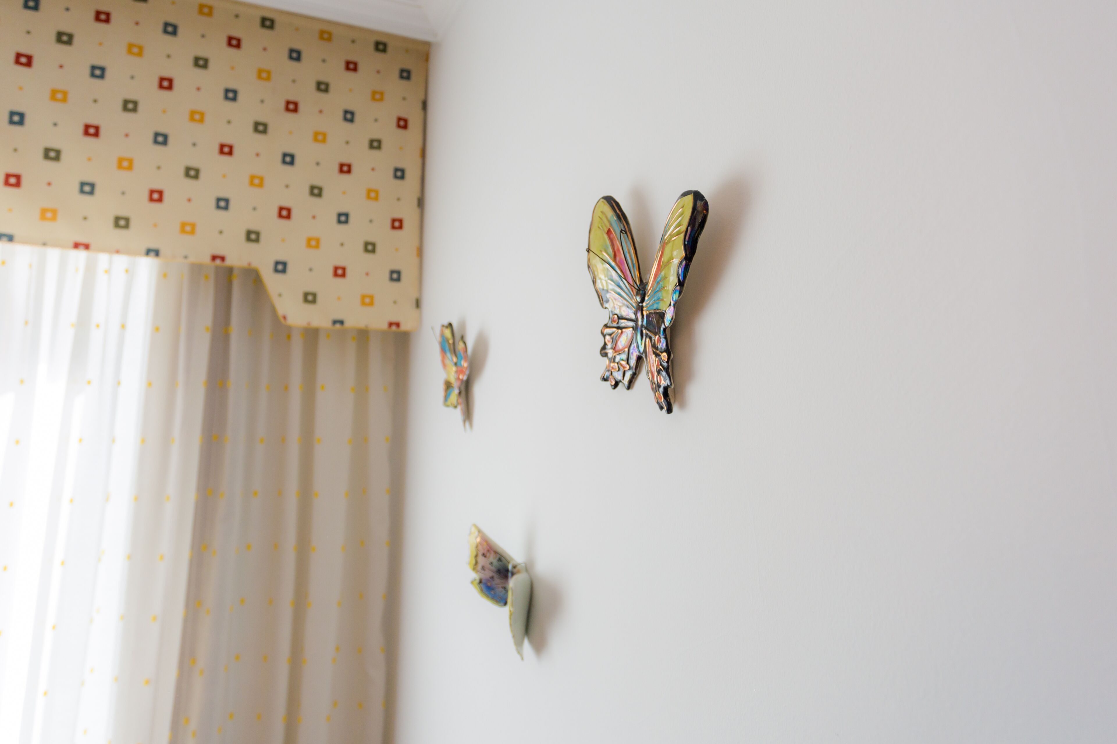 A room with a patterned curtain and butterfly wall decor.