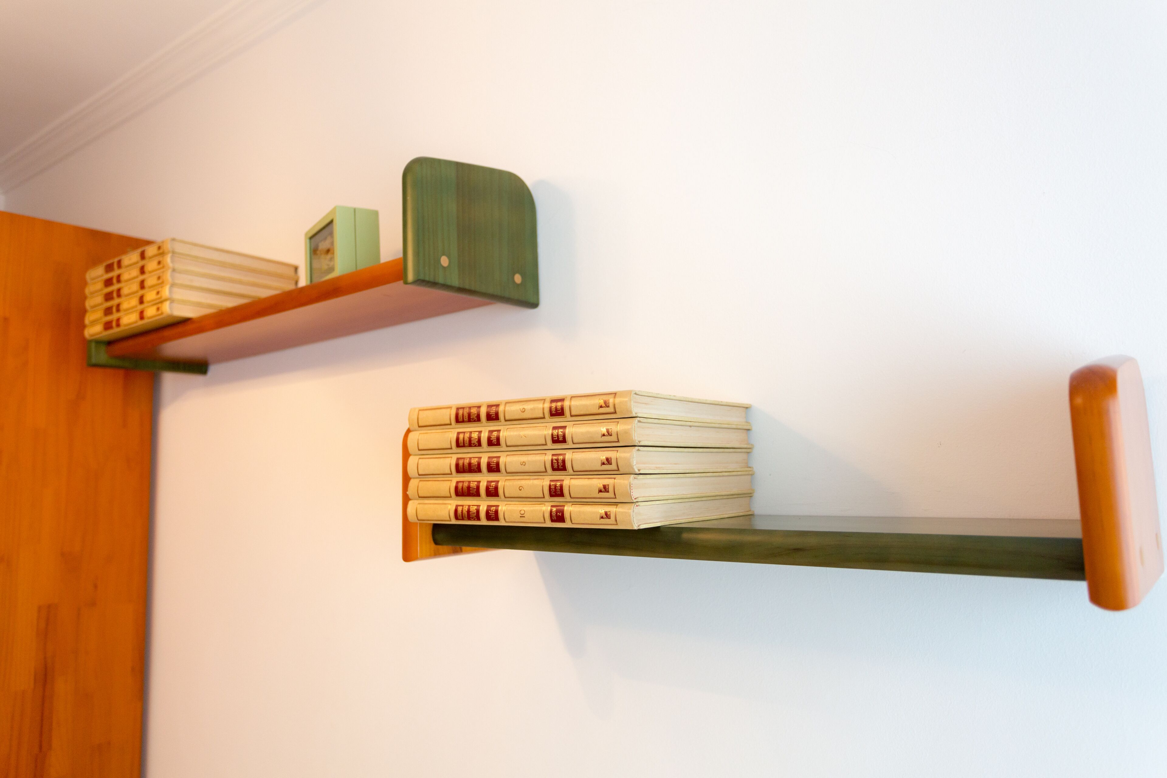 Una estantería con una pila de libros y una caja verde pequeña.