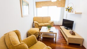 Un saló amb un sofà, una taula de centre, una televisió i una petita estant amb una planta.