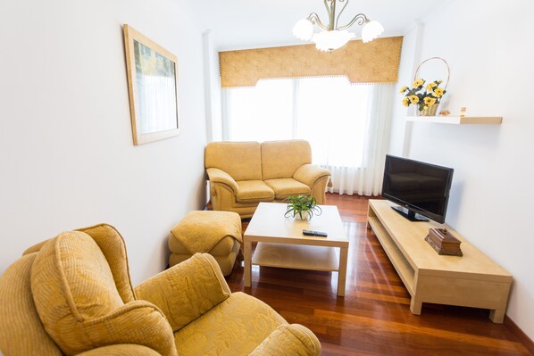 A living room with a sofa, a coffee table, a TV, and a small shelf with a plant. - House Goros II (Melide)