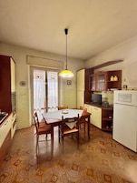 Una cucina compatta con tavolo e sedie, un lampadario e un frigorifero.