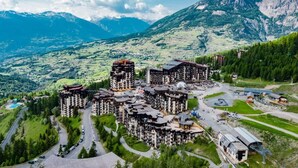 Une station de montagne comprenant plusieurs bâtiments, des routes et offrant une vue sur les montagnes environnantes.