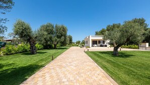 A paved pathway leading to a building with a balcony, surrounded by well-maintained grass and olive trees. - Villa La Seta by Perle di Puglia (San Vito dei Normanni)