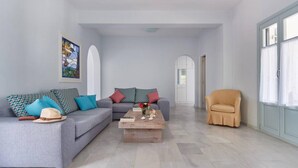 Un salón amplio con un sofá gris, una mesa de centro de madera y un sillón color crema.