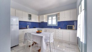 Una cocina moderna con armarios blancos, salpicadero de azulejos azules, una mesa de comedor con sillas y un microondas.
