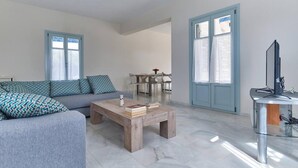 A modern living room with a sofa, coffee table, and a dining area with chairs. - Aegean Villa in Paros (Paros)