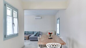 A dining area with a wooden table, white chairs, and a vase with flowers. - Aegean Villa in Paros (Paros)