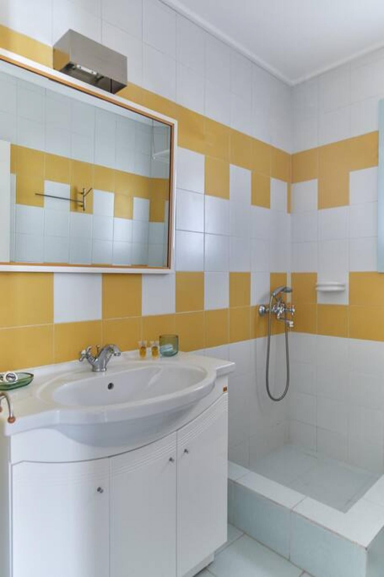 A bathroom with a sink, mirror, and shower.