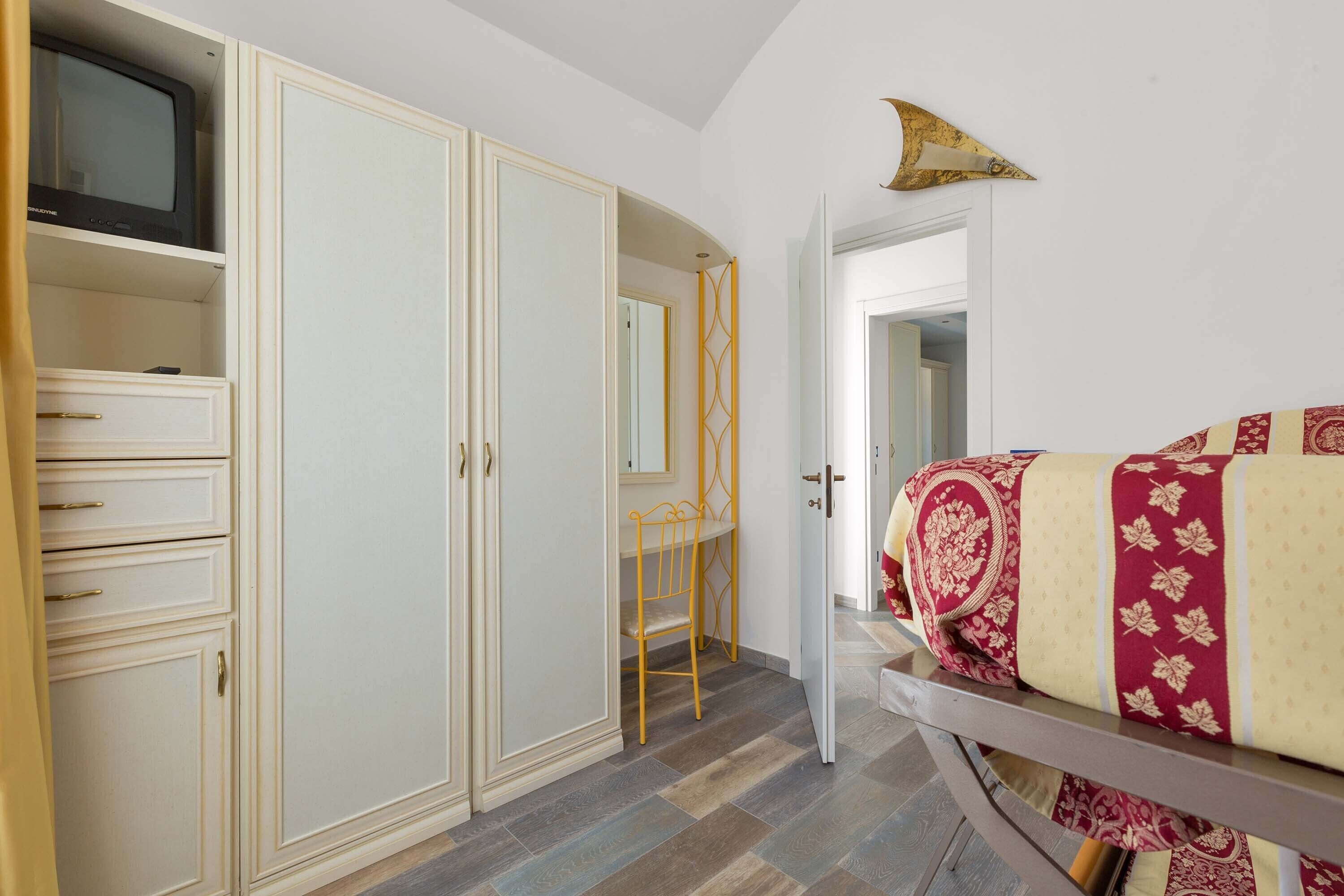 Une chambre à coucher avec un lit, une armoire, une télévision et un miroir.