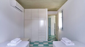 A hotel room with two beds, a wardrobe, and a checkered floor. - Santa Maria Villa in Paros (Paros)