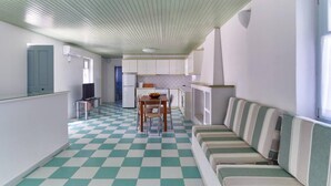 A compact kitchen with a checkered floor, a dining area with a table and chairs, and a striped sofa. - Santa Maria Villa in Paros (Paros)