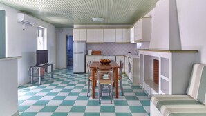 A compact kitchen with a checkered floor, a dining table with chairs, and a built-in bench. - Santa Maria Villa in Paros (Paros)