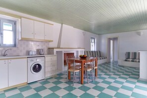 Cocina compacta con lavadora, comedor con mesa y sillas, y piso a cuadros.