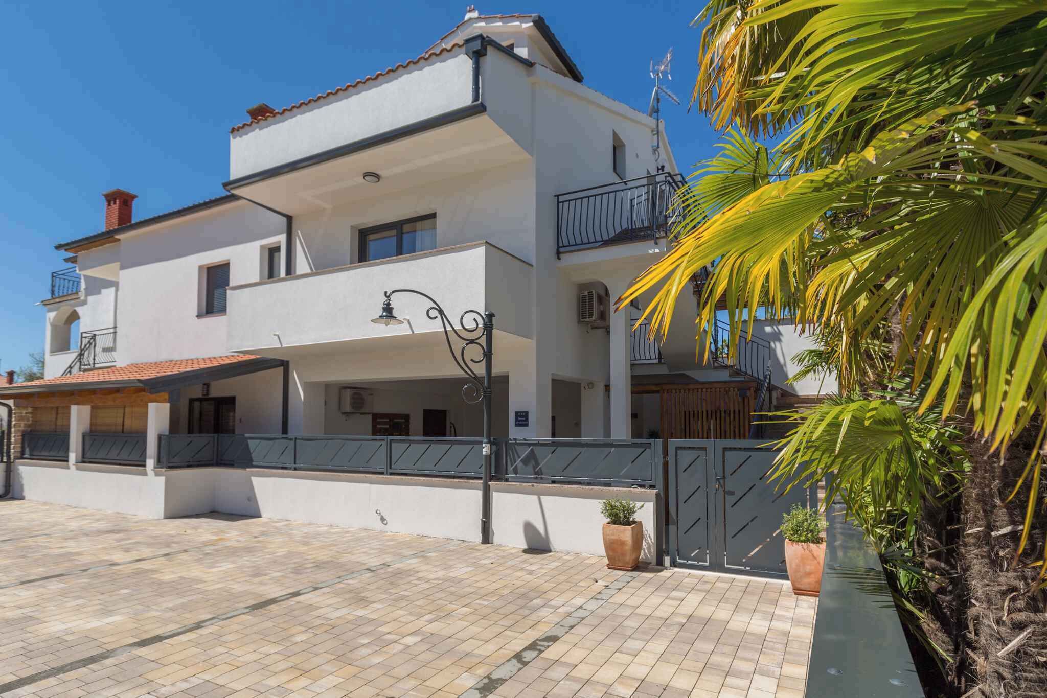 A two-story building with a balcony, a tiled roof, and a gated entrance.