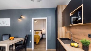 A compact kitchen with a microwave, sink, and a small dining area with chairs and a table.