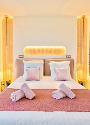 A hotel room with a large bed, two bedside tables, a headboard with a light panel, and curtains on the windows.