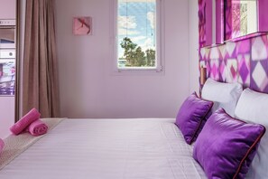 A bedroom with a bed, pillows, a window, and curtains.