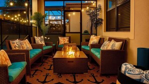 A cozy outdoor seating area with wicker furniture, a central fire feature, and a patterned rug. - Pirate Lux Villa w/ Pool, Spa & Arcades, Near Disney, coffee, waffles bar (Davenport)