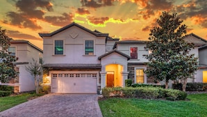 A two-story house with a garage, a driveway, and a well-maintained lawn. - Pirate Lux Villa w/ Pool, Spa & Arcades, Near Disney, coffee, waffles bar (Davenport)
