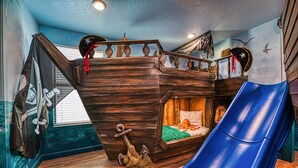 A children's playroom with a wooden bunk bed, a slide, and pirate-themed decorations. - Pirate Lux Villa w/ Pool, Spa & Arcades, Near Disney, coffee, waffles bar (Davenport)