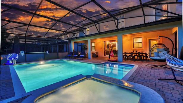 An indoor swimming pool with a glass ceiling, lounge chairs, and a hot tub. - Pirate Lux Villa w/ Pool, Spa & Arcades, Near Disney, coffee, waffles bar (Davenport)