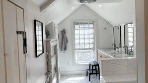 Une salle de bain moderne avec un carrelage au motif géométrique, une grande fenêtre et un banc intégré.