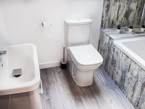 Une salle de bain équipée de toilettes, d’un lavabo et d’une baignoire.