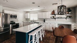 A modern kitchen with white cabinetry, a central island with bar stools, a dining table with chairs, and a hanging light fixture. - Resort Style Heated Pool close to Entertainment (Phoenix)