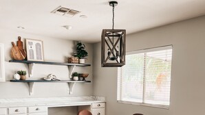 A modern kitchen with white cabinetry, a wooden dining table, and a window with blinds. - Resort Style Heated Pool close to Entertainment (Phoenix)