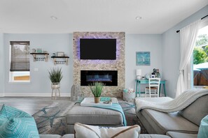 A living room with a stone fireplace, a flat-screen TV, and a cozy seating area.