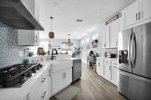 Una cocina moderna con armarios blancos, electrodomésticos de acero inoxidable y una isla central.