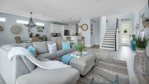A modern living room with a grey sectional sofa, a coffee table, and a staircase leading to a second floor.