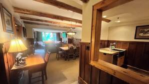 Un comedor acogedor con muebles de madera, una lámpara de mesa y suelo de piedra.