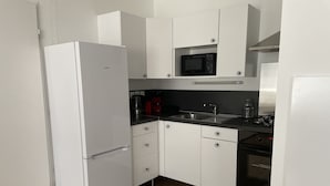 Een moderne keuken met witte kasten, een ingebouwde magnetron, een roestvrijstalen spoelbak en een gasfornuis.