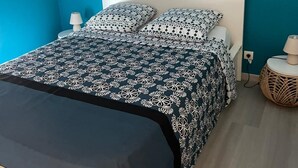 Een slaapkamer met een bed, twee nachtkastjes en een lamp aan elke kant.
